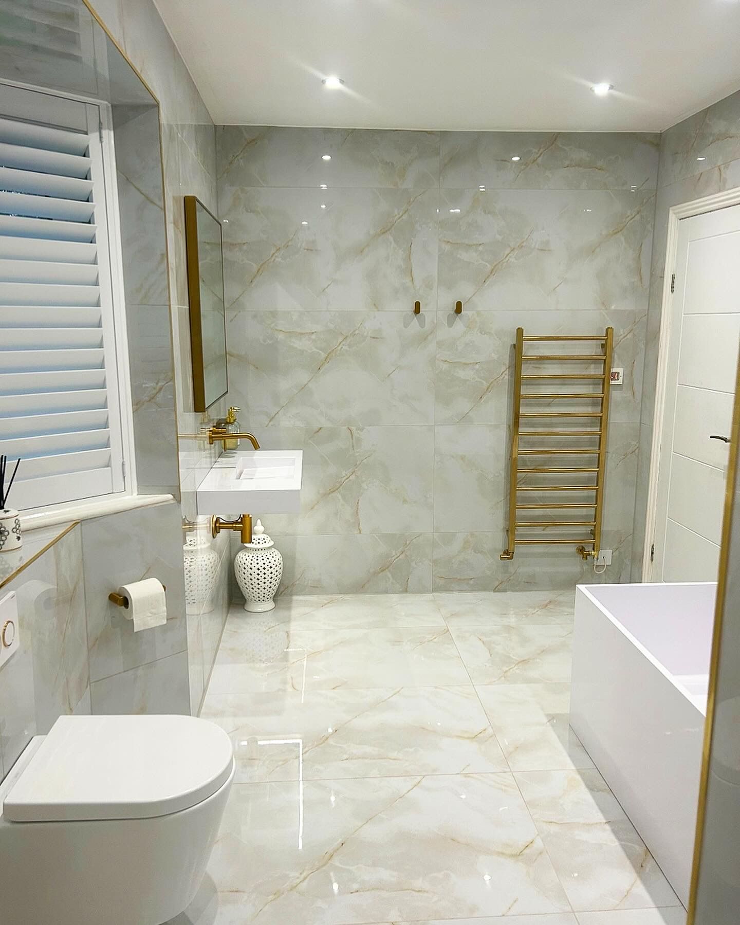 Marble and brass bathroom renovation with wall hung toilet in Epping, Essex