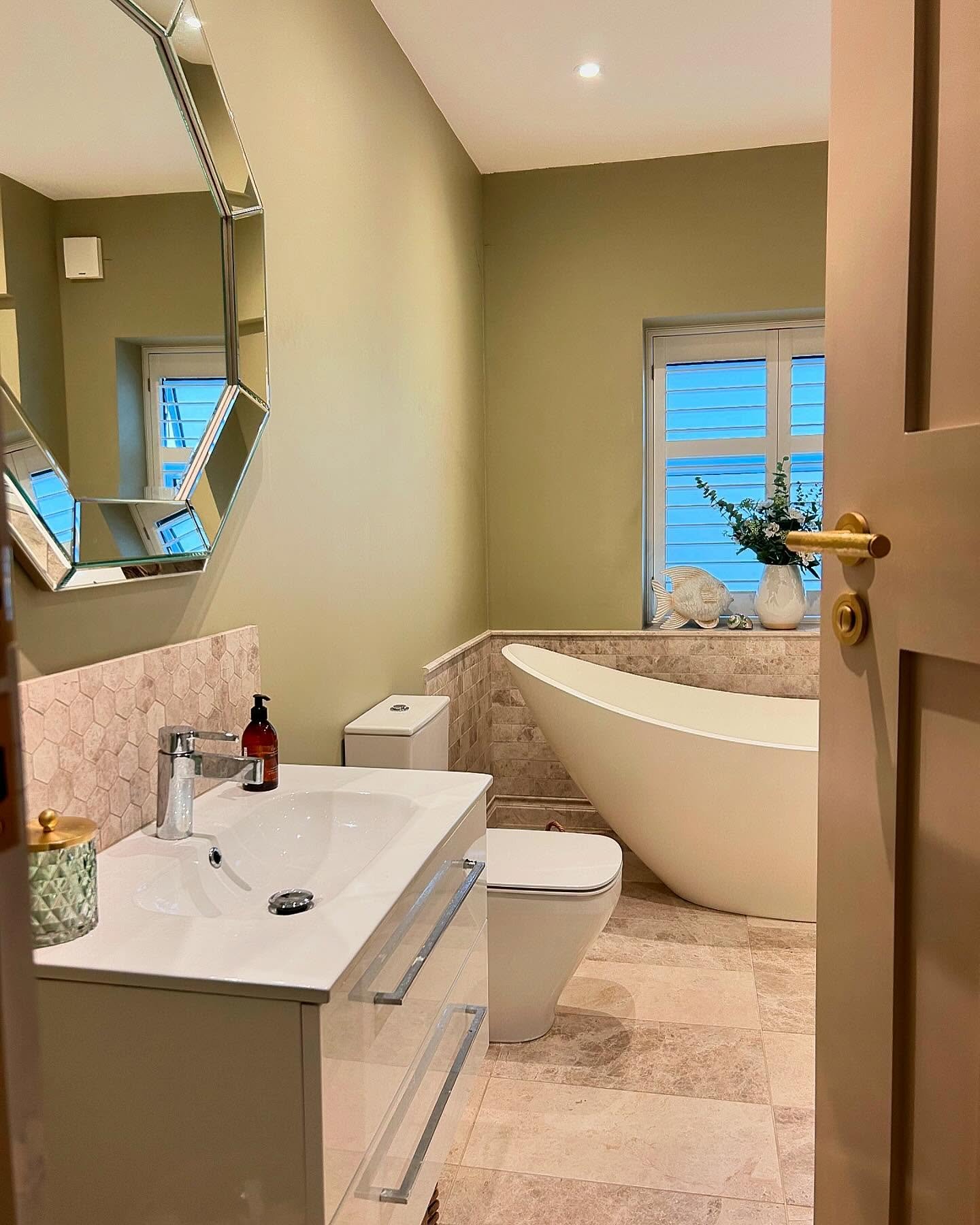 Green tiled bathroom renovation in Essex with freestanding bath